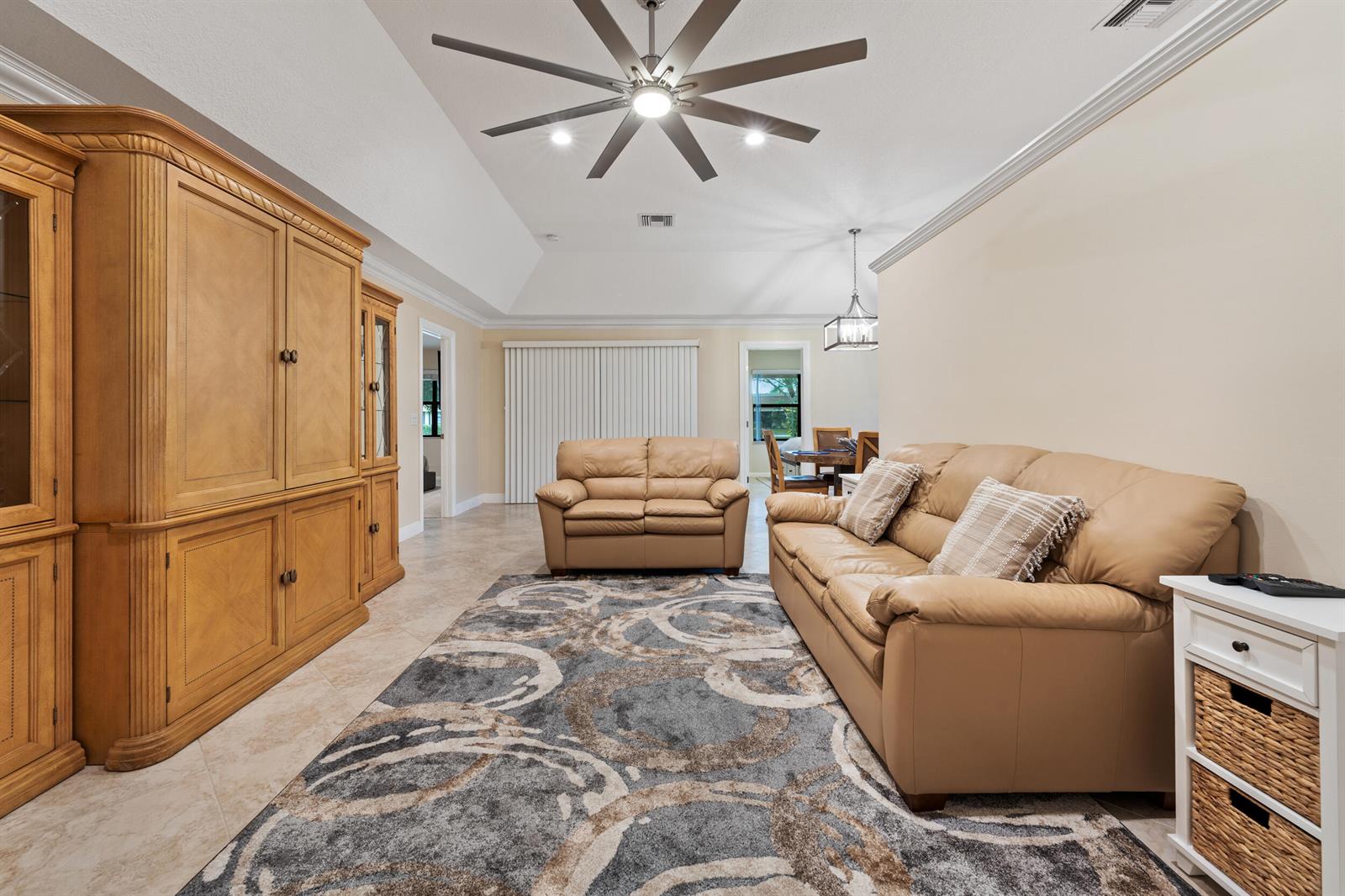 A living room features a large entertainment center, two tan leather sofas, and a patterned rug — 109 Half Moon Circle # C, Jupiter FL 33458, JUPITER, FL