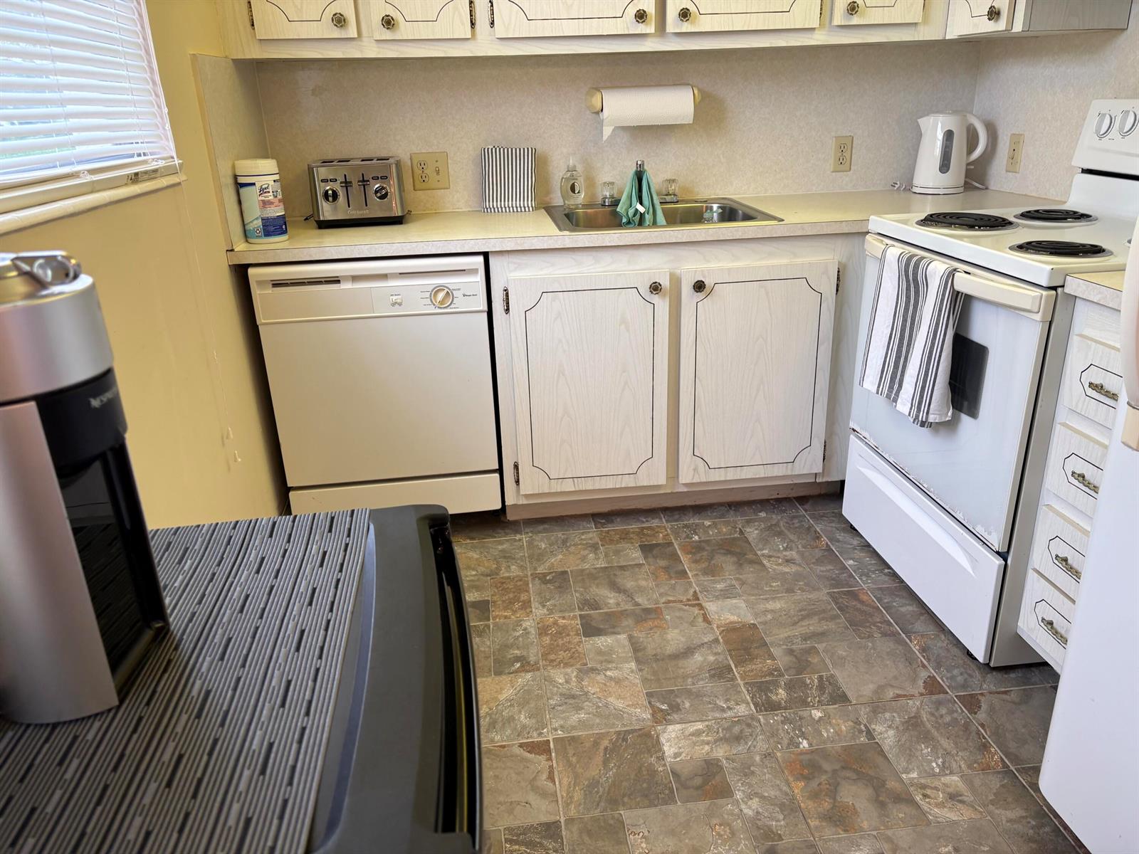 A kitchen features white cabinets, a dishwasher, a stove, and a sink with tile flooring — 112 Preston Way # C, Boca Raton FL 33434, BOCA RATON, FL