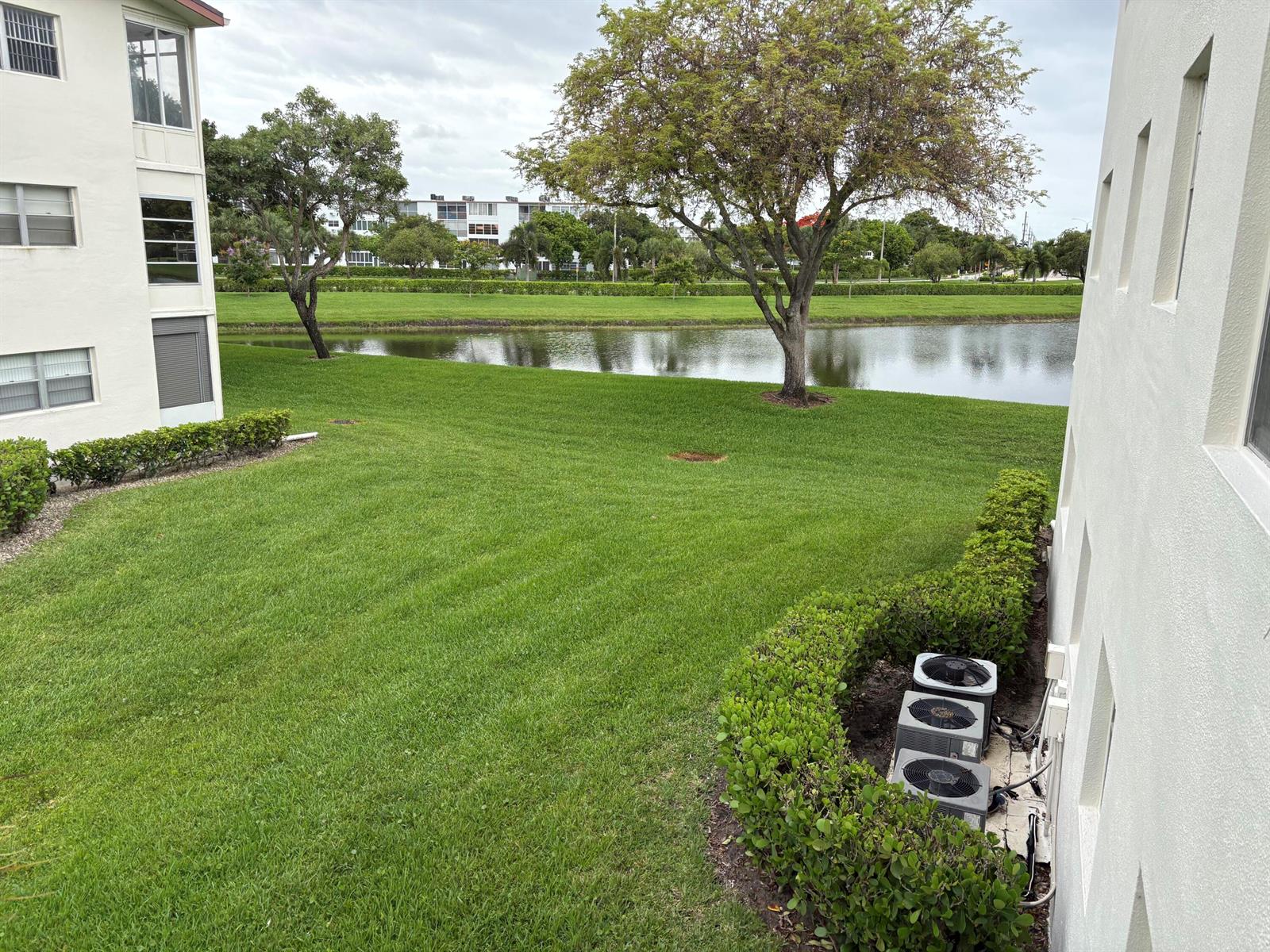 An elevated view shows a grassy lawn, a pond, trees, and apartment building exteriors — 112 Preston Way # C, Boca Raton FL 33434, BOCA RATON, FL