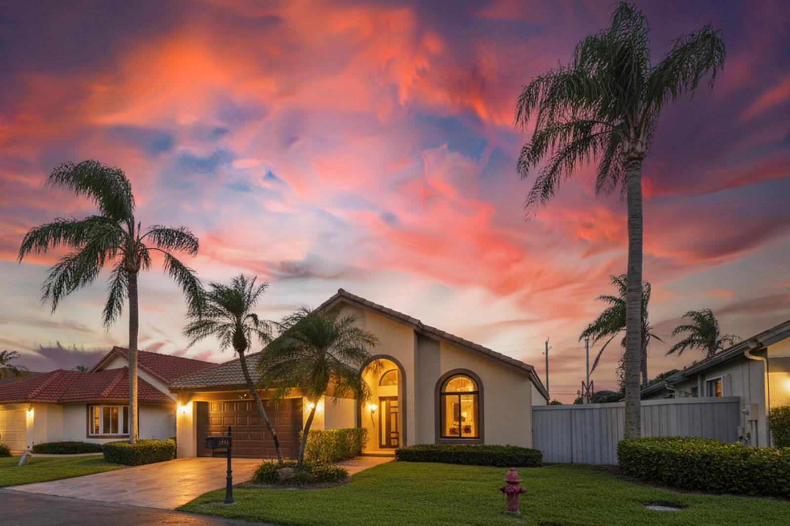 A single-story house with a garage and palm trees under a vibrant sunset sky — 169 Executive Circle, Boynton Beach FL 33436, BOYNTON BEACH, FL