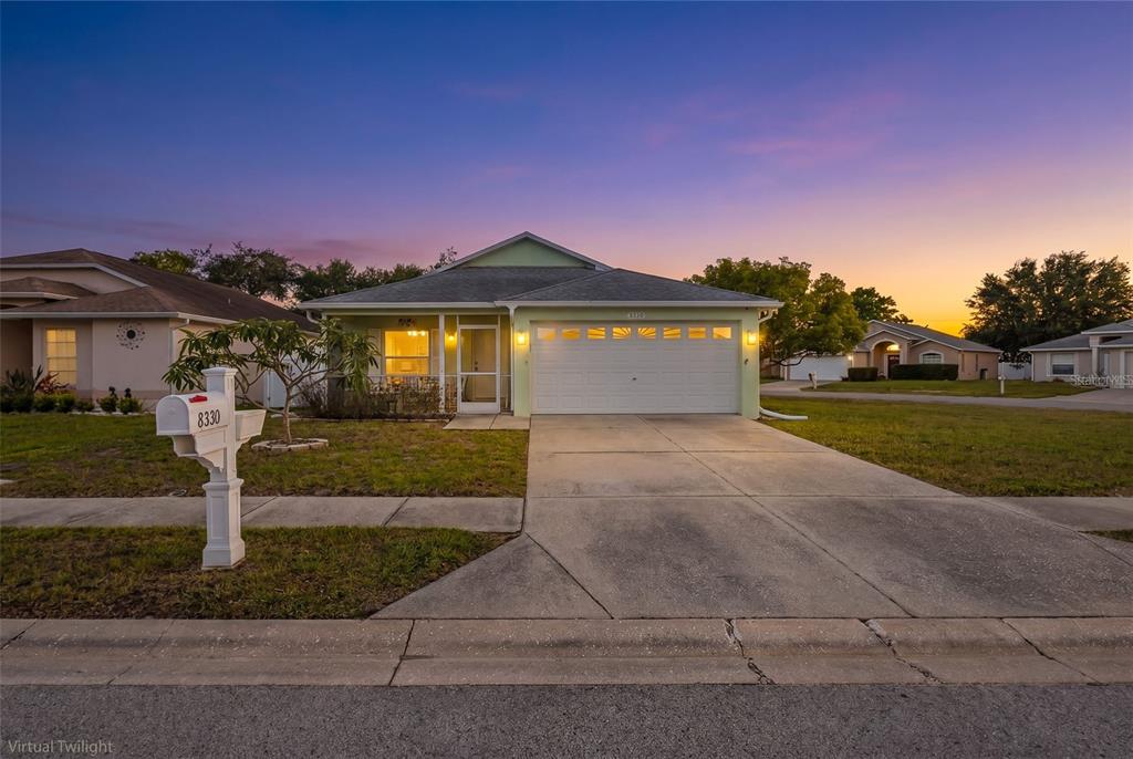 A single-story house with a white garage door, a concrete driveway, and a mailbox at sunset — 8330 GOLDOME DRIVE, PORT RICHEY, FL