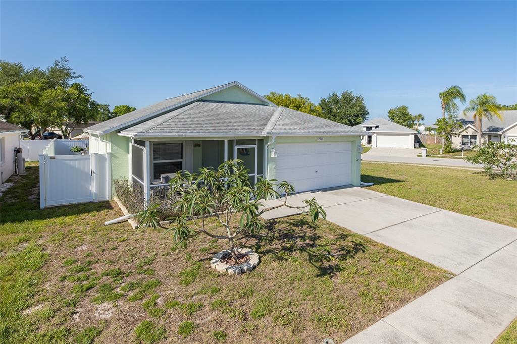 A light green single-story house with a white garage and a screened-in front porch — 8330 GOLDOME DRIVE, PORT RICHEY, FL