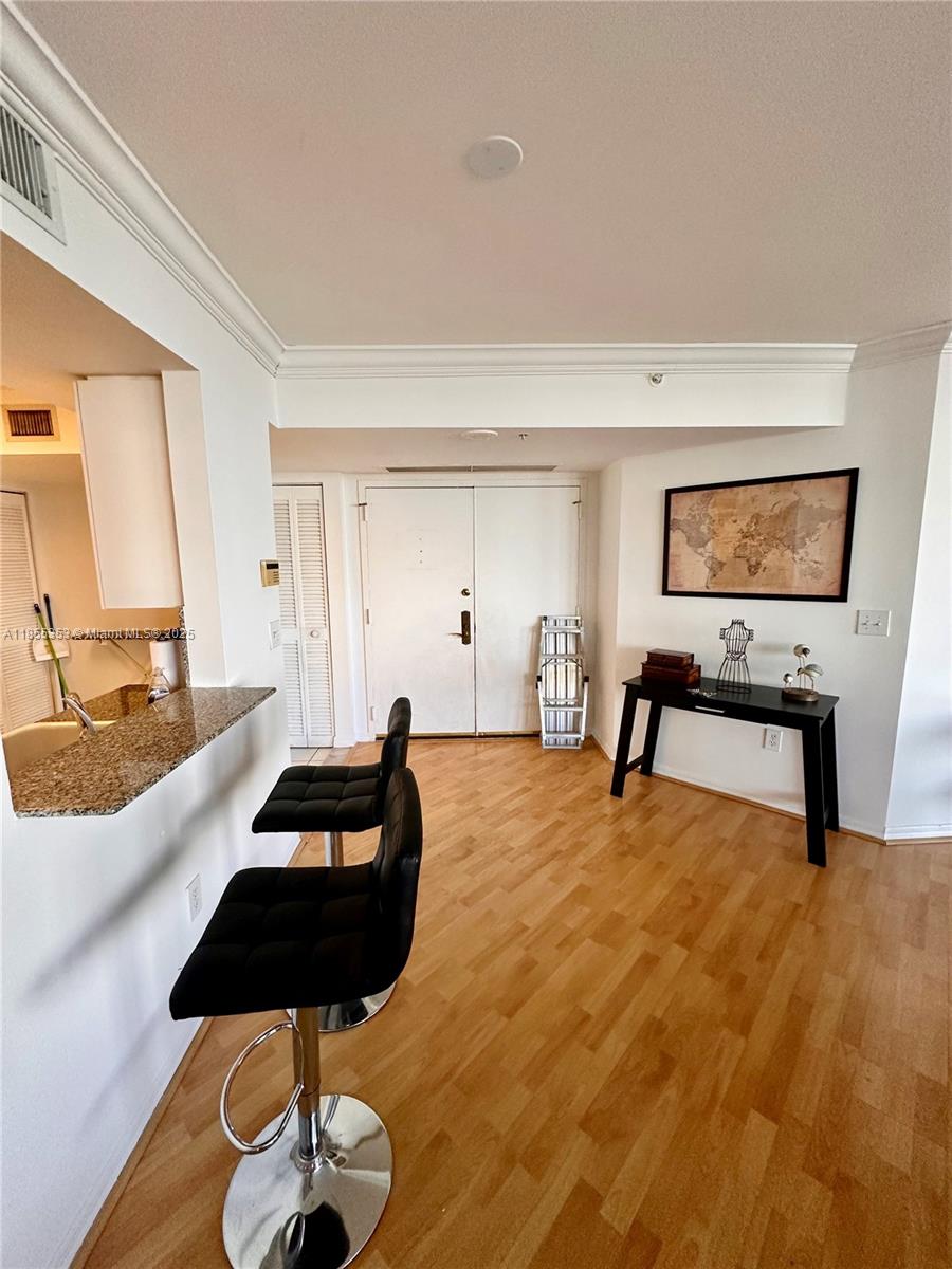 A kitchen breakfast bar with two black stools faces a hallway with a wooden floor — 6301 Collins Ave # 806, Miami Beach FL 33141, MIAMI BEACH, FL