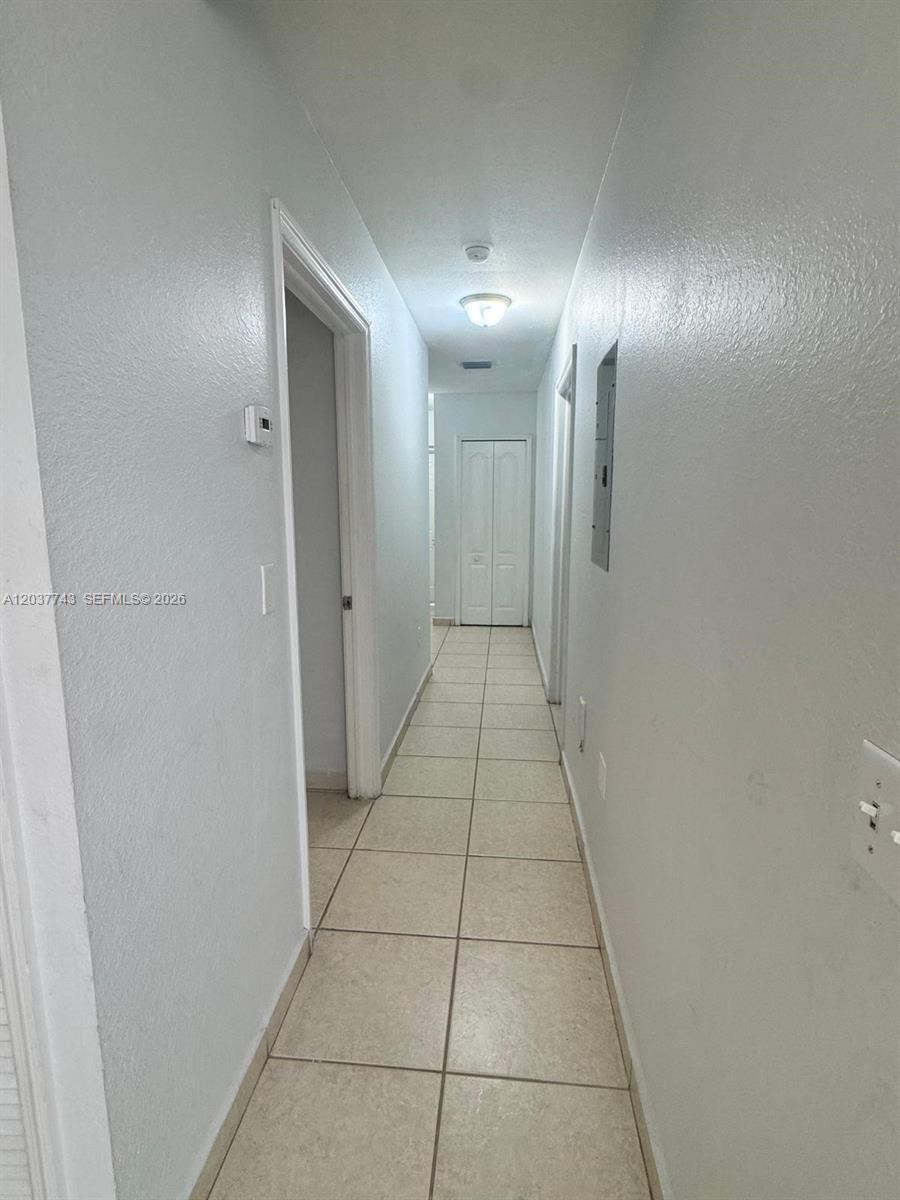 A narrow hallway features light-colored tile flooring, white walls, and a recessed ceiling light — 7502 NW 175th St # 7502, Hialeah FL 33015, HIALEAH, FL
