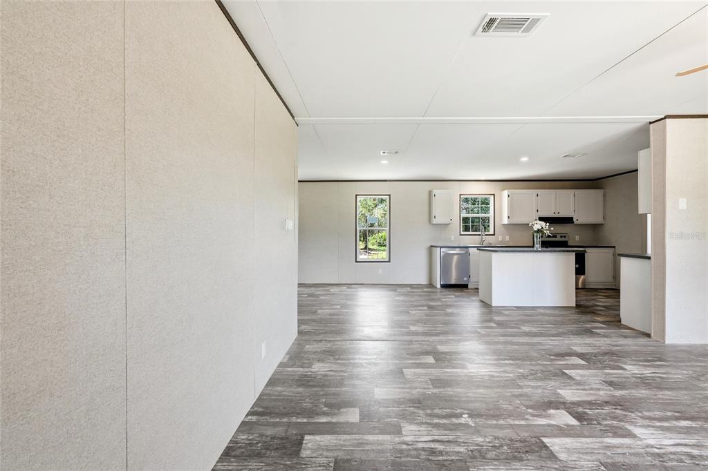 An open-concept kitchen and living area features light-colored walls, wood-look flooring, and a central island — 17381 NW 262ND STREET, OKEECHOBEE, FL