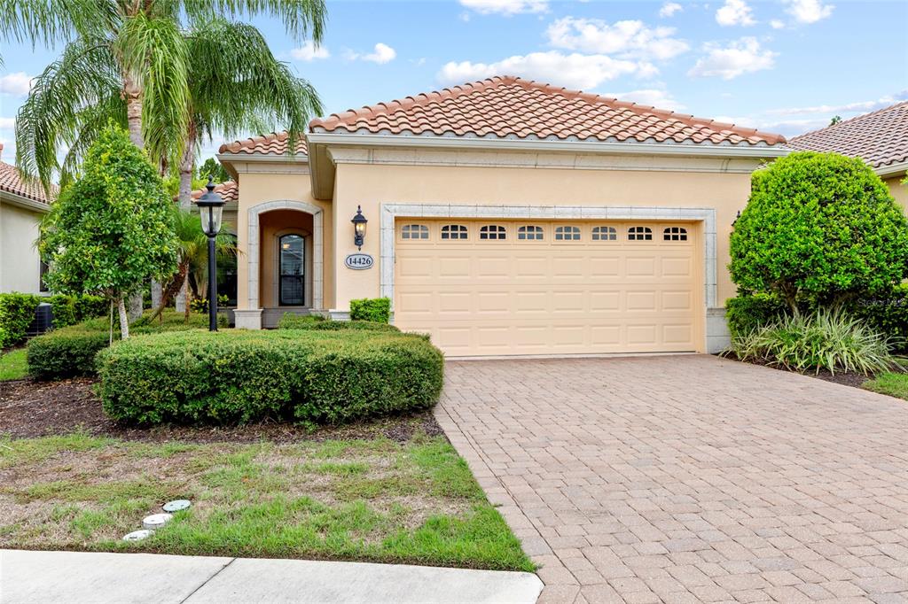 A single-story house with a beige stucco exterior, a tile roof, and a two-car garage — 14426 WHITEMOSS TERRACE, LAKEWOOD RANCH, FL
