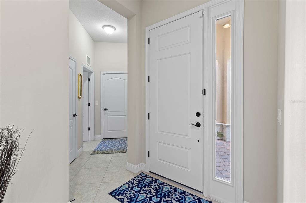A bright entryway features a white front door with a sidelight, tile flooring, and rugs — 14426 WHITEMOSS TERRACE, LAKEWOOD RANCH, FL