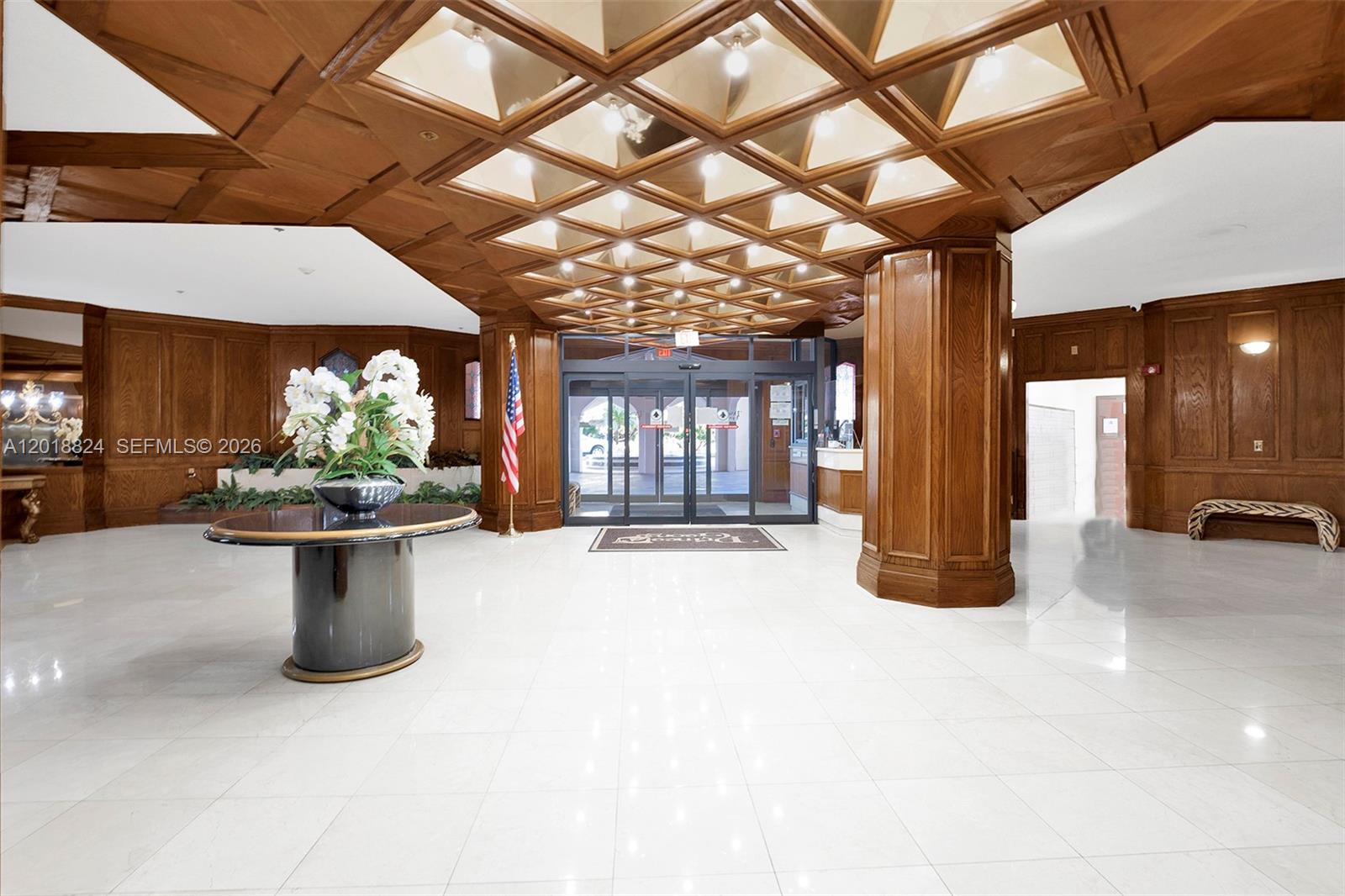 A spacious lobby features wood-paneled walls, a coffered ceiling, and a large central pedestal table — 1865 S Ocean Dr # 4C, Hallandale Beach FL 33009, HALLANDALE BEACH, FL