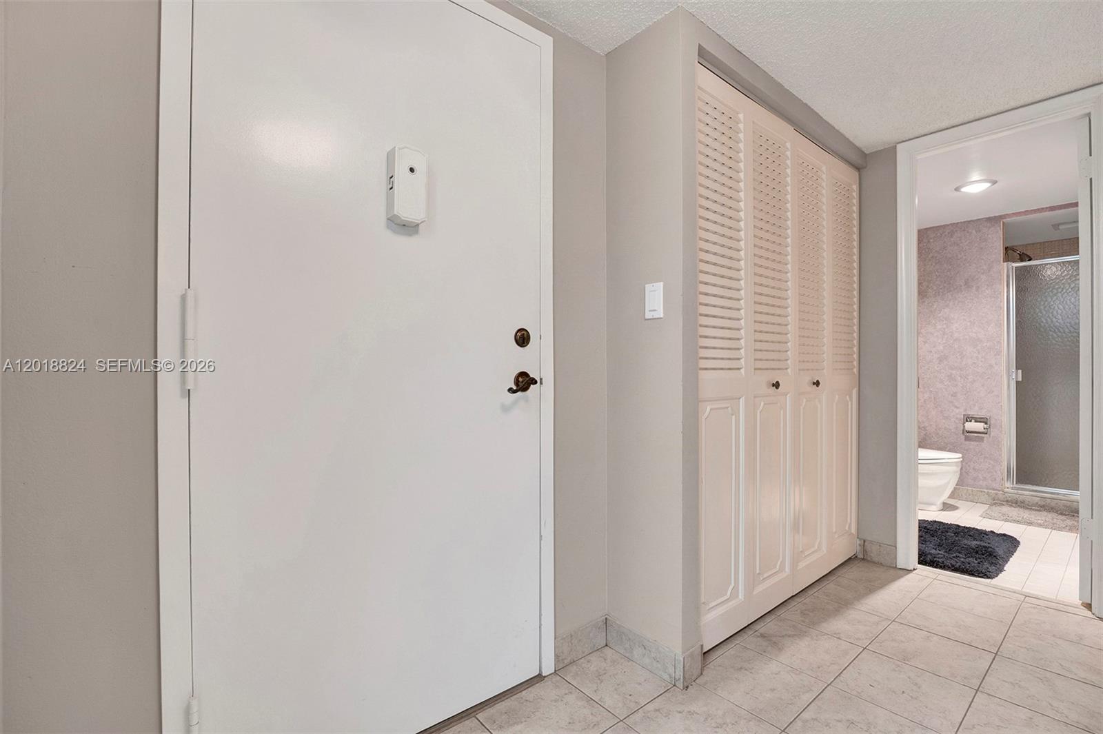 A white door and louvered closet doors lead to a tiled bathroom with a shower — 1865 S Ocean Dr # 4C, Hallandale Beach FL 33009, HALLANDALE BEACH, FL