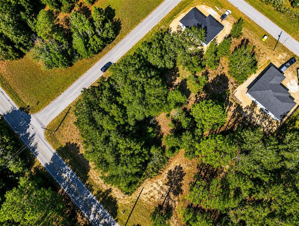 An aerial view shows a wooded residential lot situated between two houses and two roads — TBD SW MARINE BLVD, DUNNELLON, FL