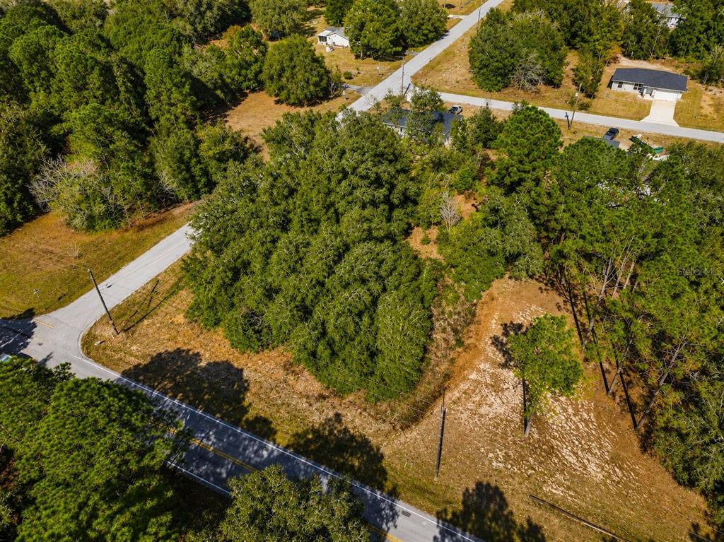 An aerial view shows a wooded corner lot bordered by two paved roads — TBD SW MARINE BLVD, DUNNELLON, FL