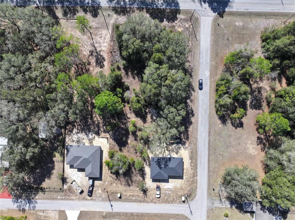 An aerial view shows two newly constructed houses on a wooded lot near a road — TBD SW MARINE BLVD, DUNNELLON, FL