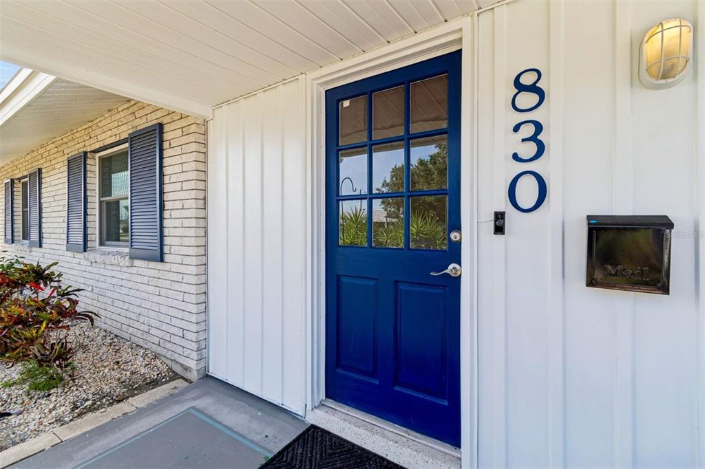 A blue front door with a window pane sits next to a wall-mounted mailbox — 830 LA JOLLA AVENUE, SUN CITY CENTER, FL