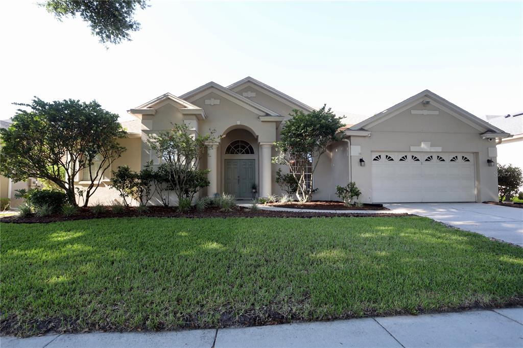 A single-story house with a beige stucco exterior, a two-car garage, and a front lawn — 7902 GLEN CREST WAY, ORLANDO, FL