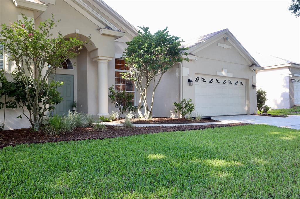 A single-story house with a beige stucco exterior, a two-car garage, and a front lawn — 7902 GLEN CREST WAY, ORLANDO, FL