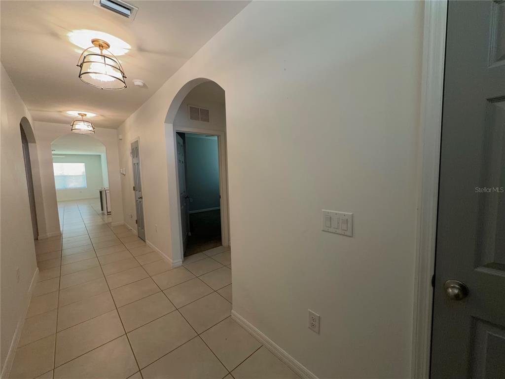 A tiled hallway features arched doorways, recessed lighting, and a grey door on the right — 27956 ARROWHEAD CIRCLE, PUNTA GORDA, FL