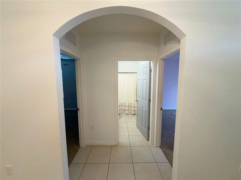 A tiled hallway with an arched entryway leads to a bathroom and two adjacent rooms — 27956 ARROWHEAD CIRCLE, PUNTA GORDA, FL