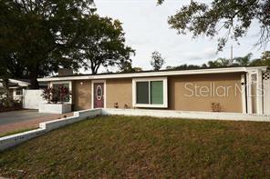 A living room with a sofa, dining area, and kitchen with white cabinets and bar seating — 4433 W OKLAHOMA AVENUE, TAMPA, FL