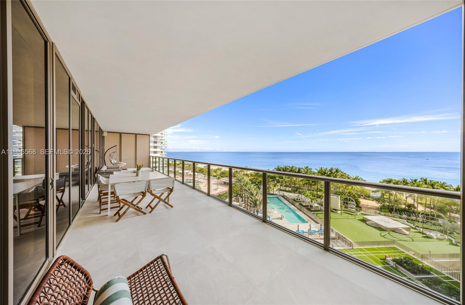 A spacious balcony features a dining set, lounge chair, and glass railings overlooking the ocean — 9705 Collins Ave # 802N, Bal Harbour FL 33154, BAL HARBOUR, FL