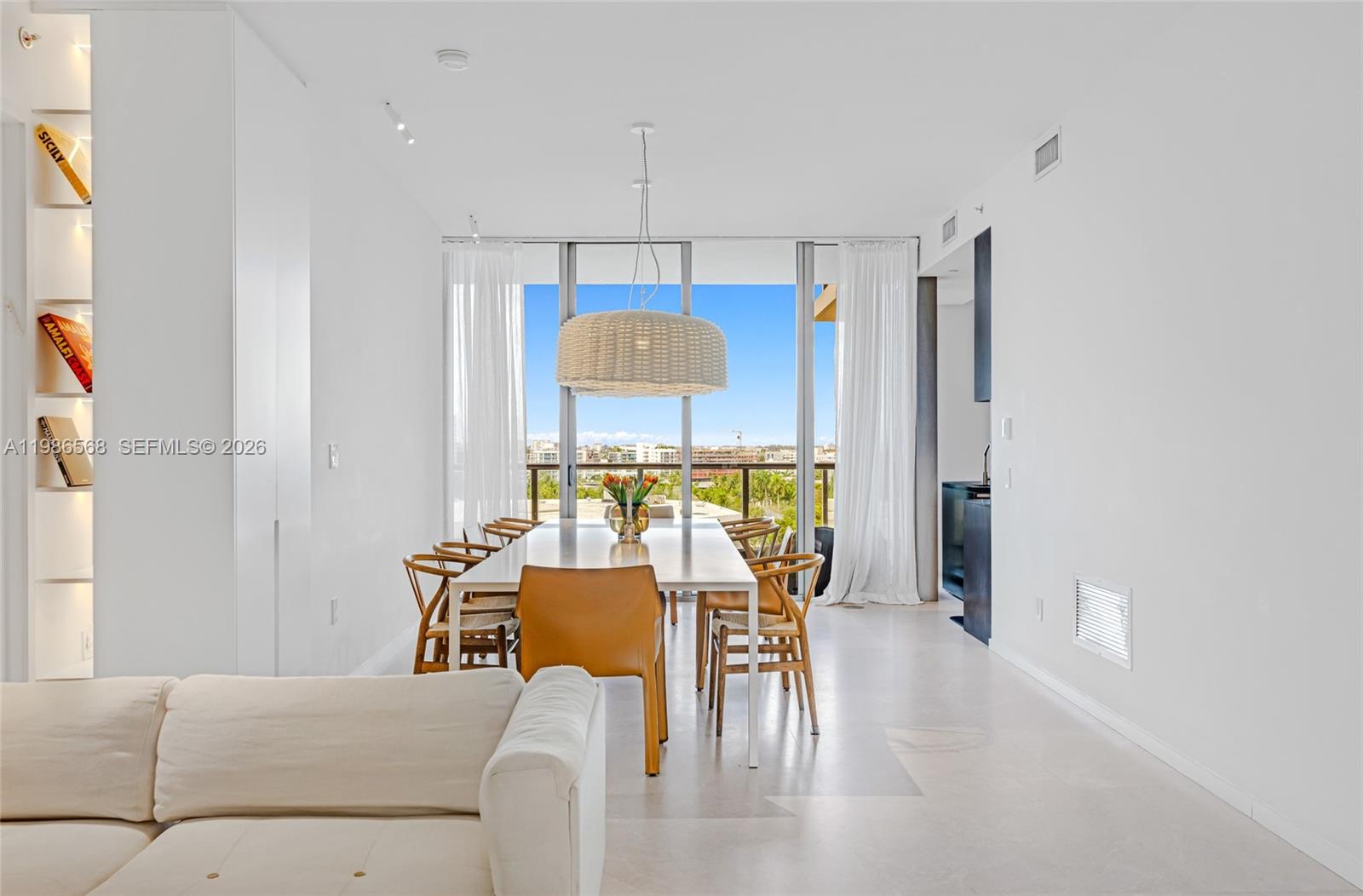 A bright dining room features a long white table, woven chairs, and floor-to-ceiling windows — 9705 Collins Ave # 802N, Bal Harbour FL 33154, BAL HARBOUR, FL