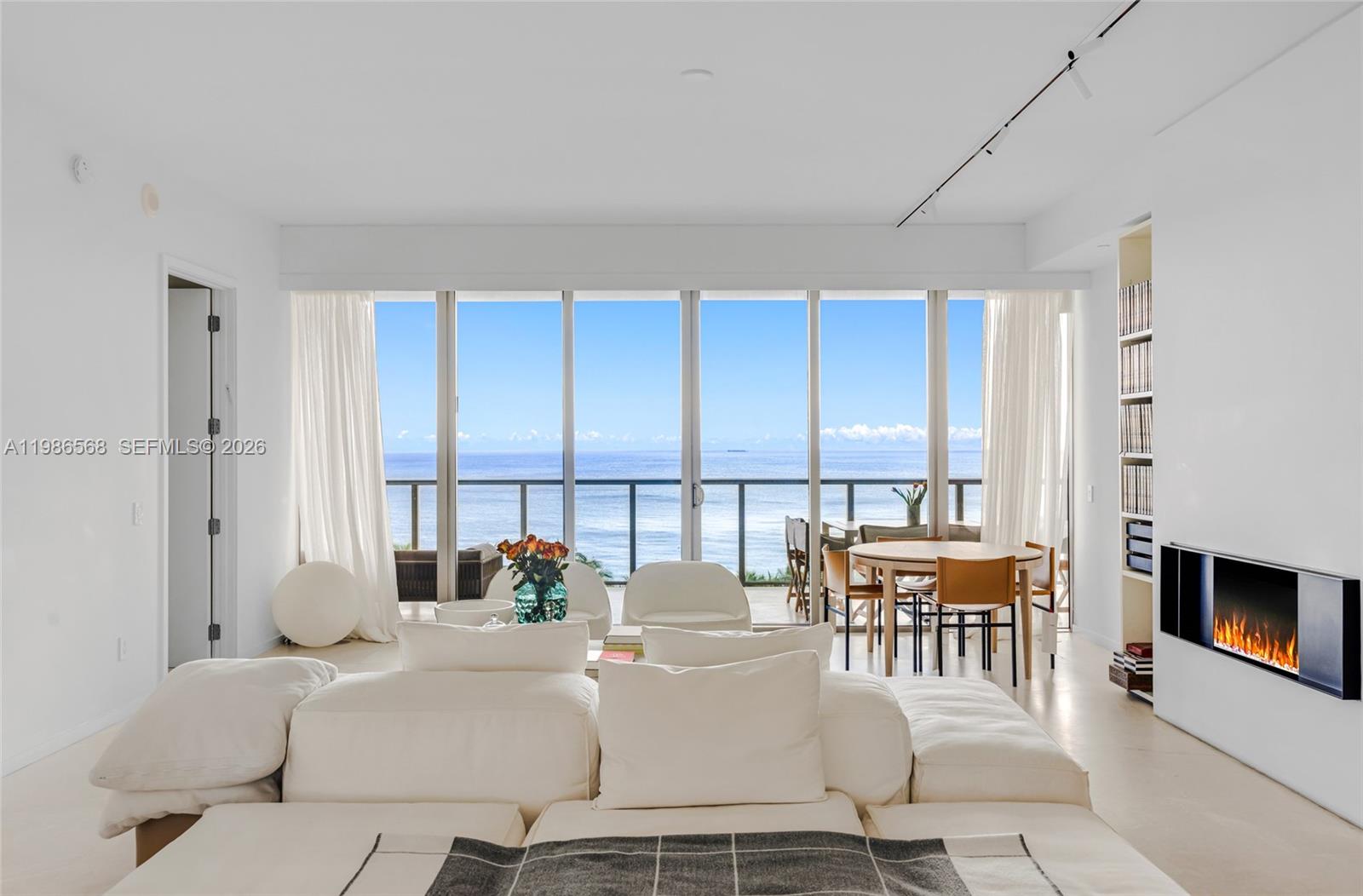 A bright living room features a white sectional sofa, a fireplace, and floor-to-ceiling ocean views — 9705 Collins Ave # 802N, Bal Harbour FL 33154, BAL HARBOUR, FL