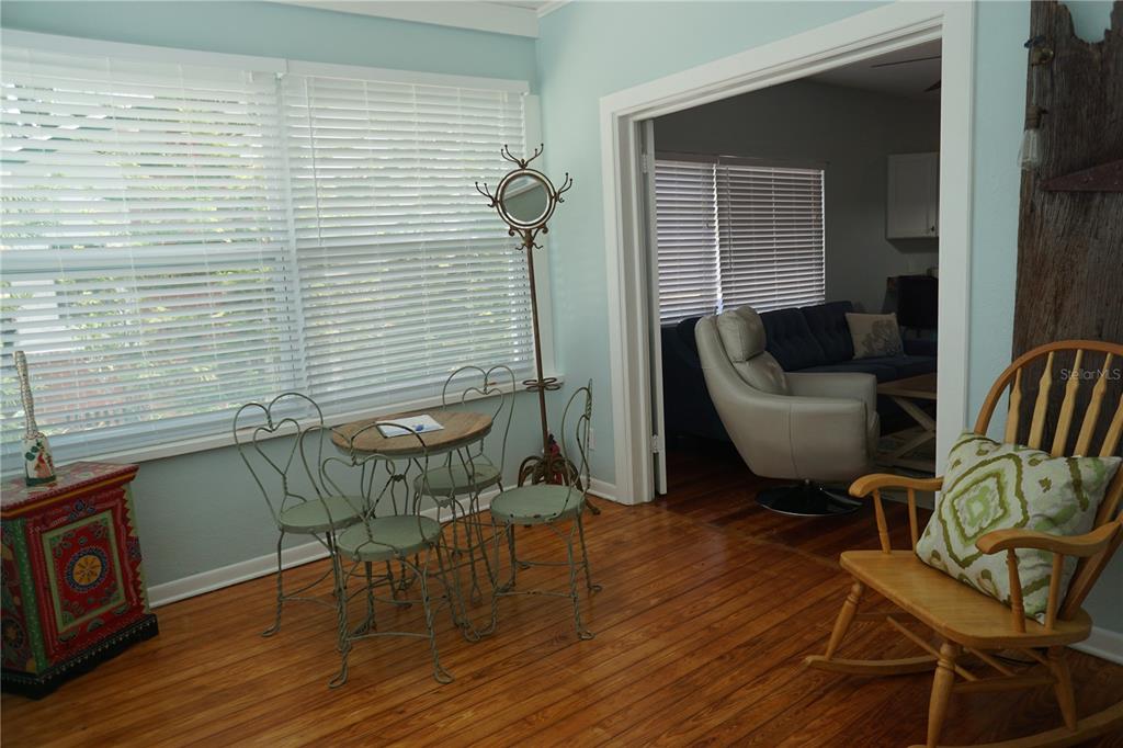 A sunroom with hardwood floors features a small bistro set, a rocking chair, and windows — 601 N OSCEOLA AVENUE, CLEARWATER, FL