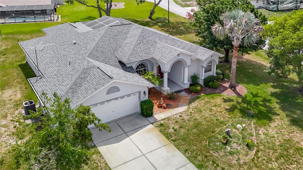 An aerial view of a single-story house with a gray shingled roof and driveway — 8206 PINEHURST DRIVE, SPRING HILL, FL