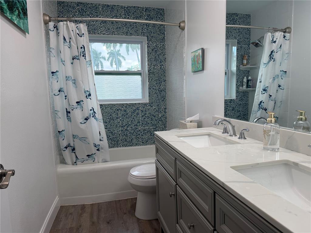 A bathroom features a double vanity, a toilet, and a bathtub with blue mosaic tile — 4620 7TH AVENUE W, BRADENTON, FL