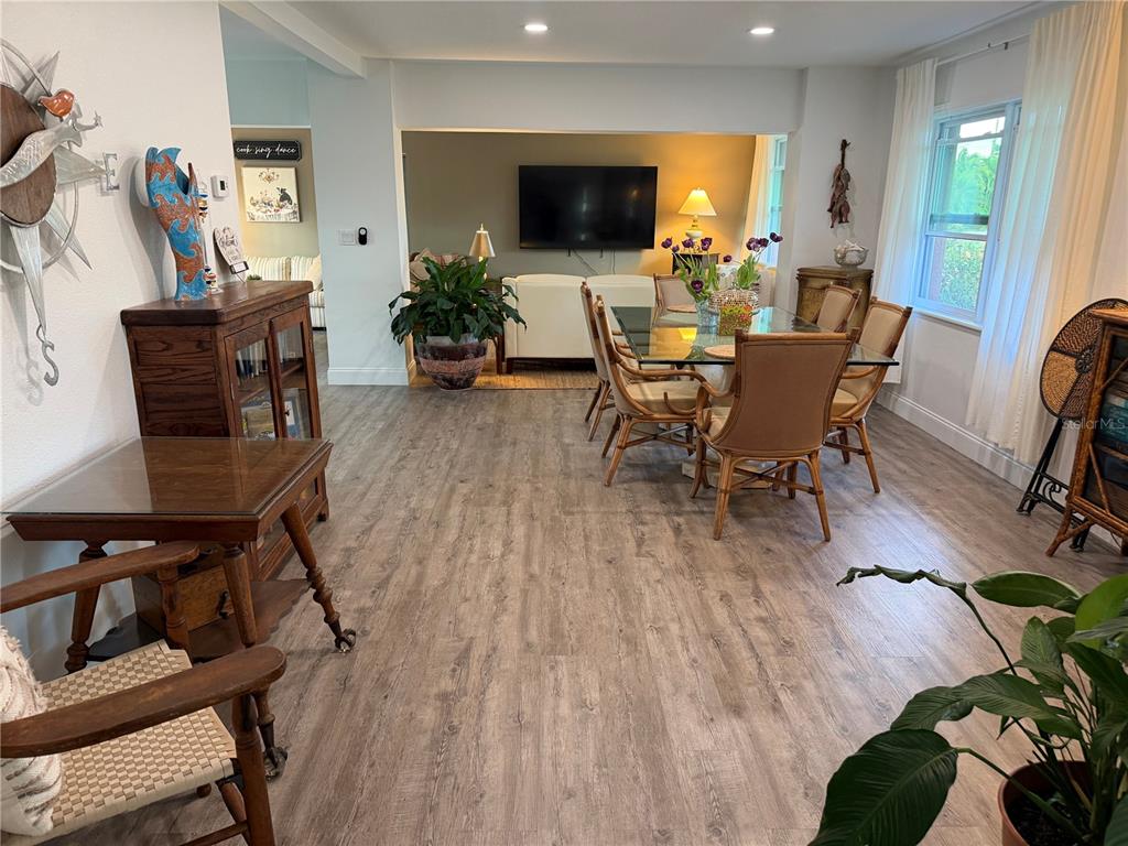 A dining area with a glass table and rattan chairs opens into a living room — 4620 7TH AVENUE W, BRADENTON, FL