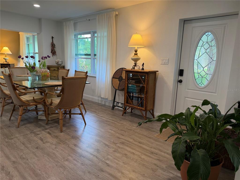 A dining area with a glass table, rattan chairs, and a white front door — 4620 7TH AVENUE W, BRADENTON, FL
