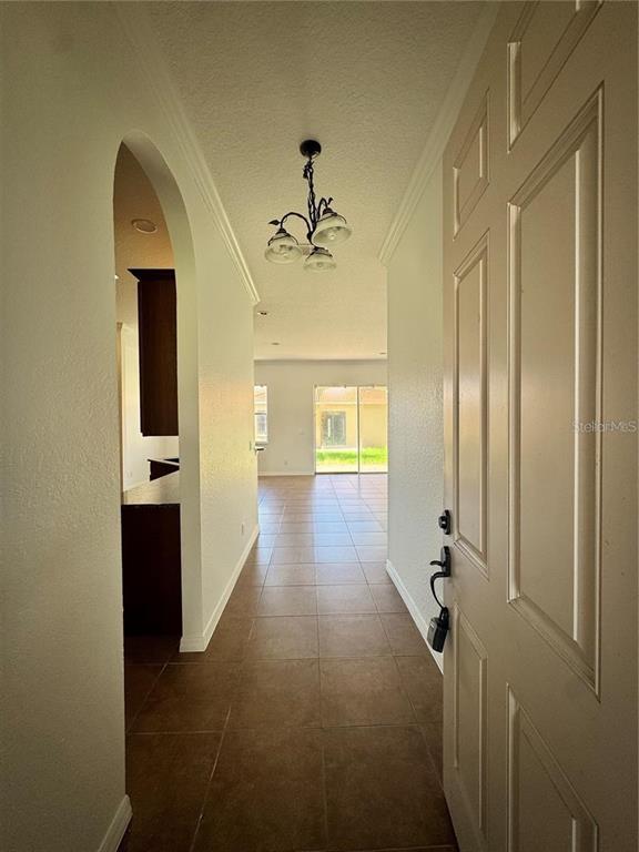 A view from an open front door into a tiled hallway with a hanging light fixture — 449 BAY LEAF DRIVE, POINCIANA, FL