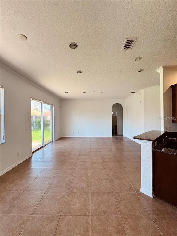 An open-concept living area features tan tile flooring, recessed lighting, and a sliding glass door — 449 BAY LEAF DRIVE, POINCIANA, FL