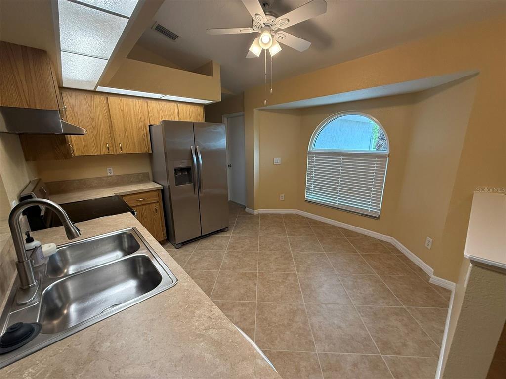 A kitchen features light wood cabinets, stainless steel appliances, and a tiled dining area — 7306 TOTEM AVENUE, NORTH PORT, FL