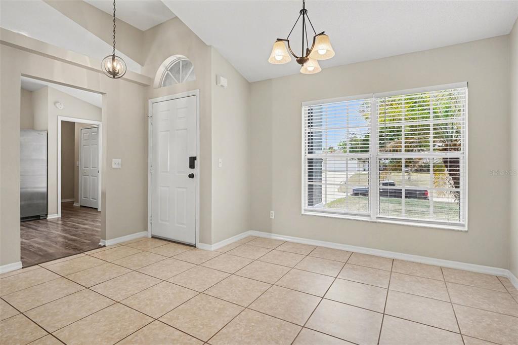 A dining area features beige tile flooring, a vaulted ceiling, and a chandelier near windows — 5626 S LOMA VISTA COURT, DAVENPORT, FL
