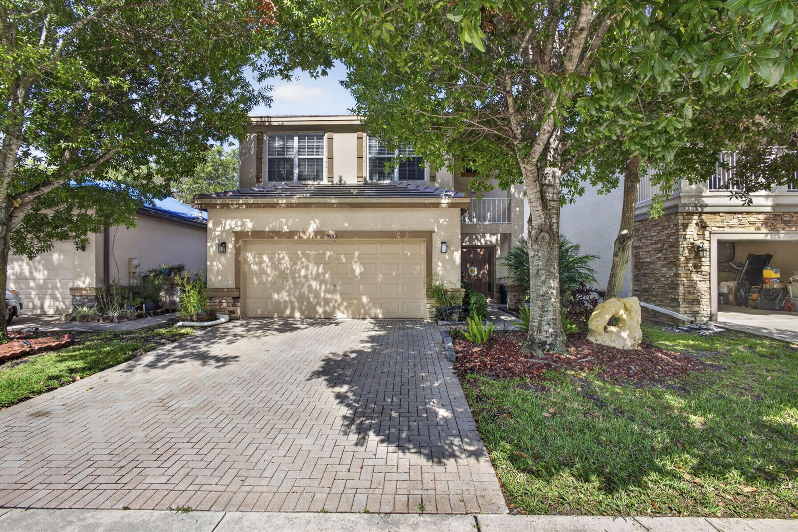 A two-story suburban house features a paved driveway, a two-car garage, and mature trees — 5953 Asturian Trail, Lake Worth FL 33449, LAKE WORTH, FL