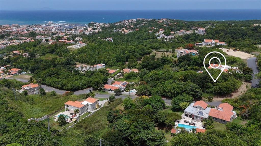 An aerial view shows a residential neighborhood with houses, lush greenery, and a distant coastline — 22 HARBOUR LIGHTS UNIT 22, HUMACAO, PR