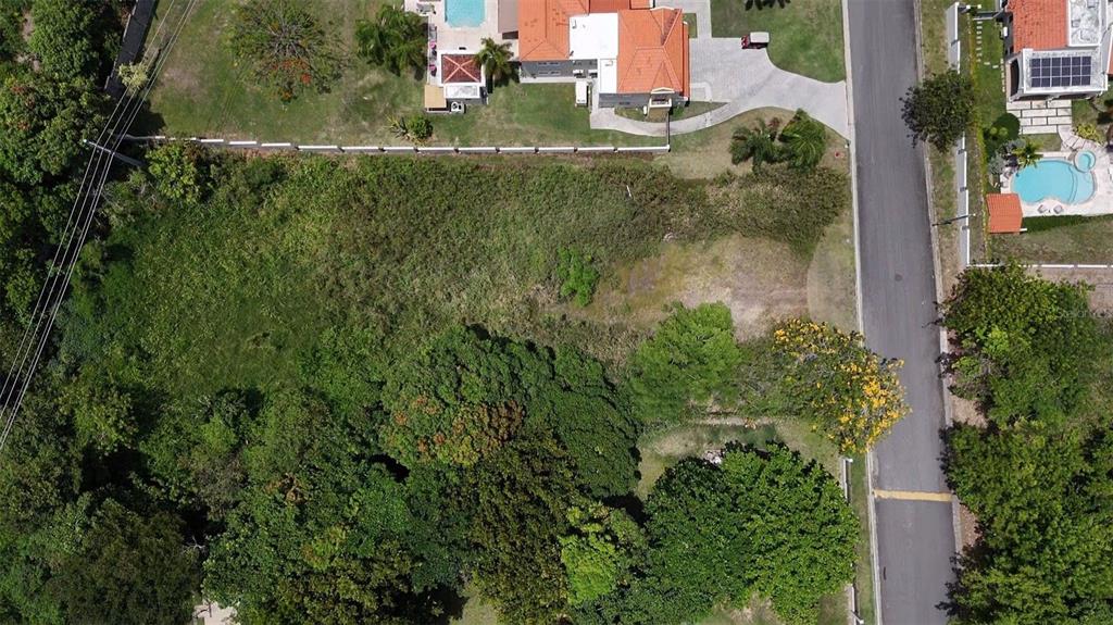 An aerial view shows a vacant, grass-covered residential lot situated next to a paved road — 22 HARBOUR LIGHTS UNIT 22, HUMACAO, PR