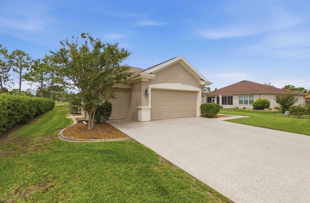 A tan single-story house with a two-car garage and a concrete driveway — 12716 SE 91ST TERRACE ROAD, SUMMERFIELD, FL