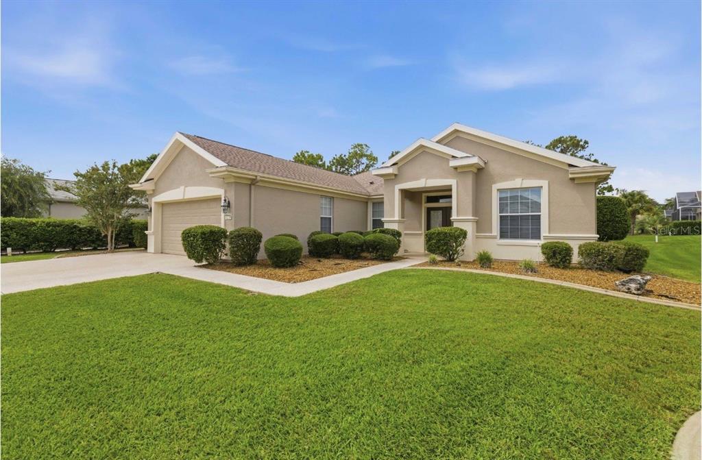 A single-story beige house with a two-car garage and a manicured front lawn — 12716 SE 91ST TERRACE ROAD, SUMMERFIELD, FL