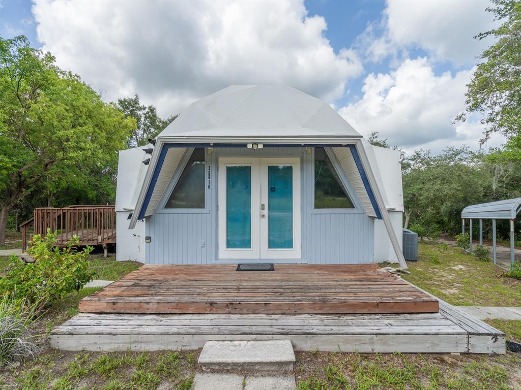 A white geodesic dome house features a light blue facade, double front doors, and wooden decking — 30810 NE 78 STREET, FORT MC COY, FL