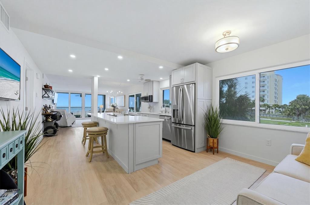 A bright, open-concept kitchen features a white island, stainless steel appliances, and ocean views — 555 THE ESPLANADE N UNIT 205, VENICE, FL
