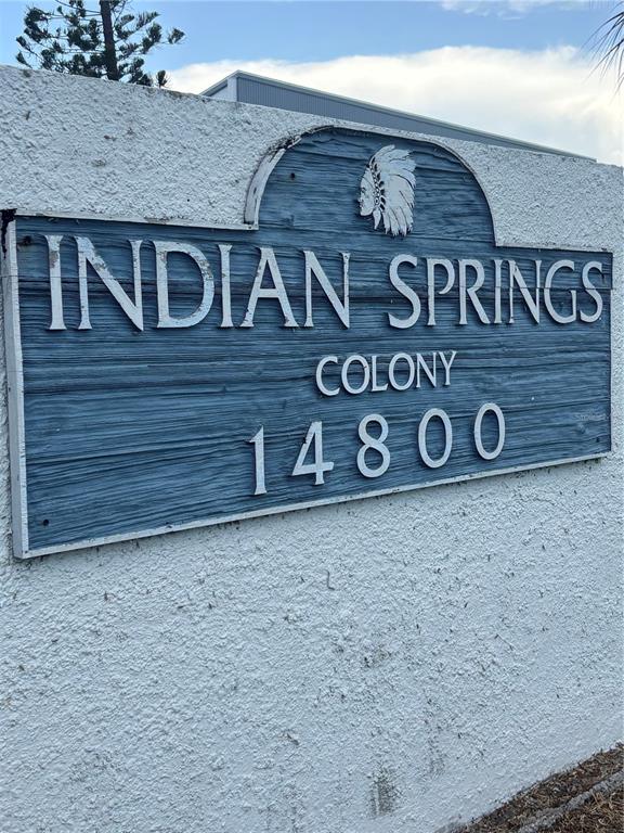 A blue wooden sign with white lettering reads Indian Springs Colony 14800 on a wall — 14800 WALSINGHAM ROAD UNIT 614, LARGO, FL