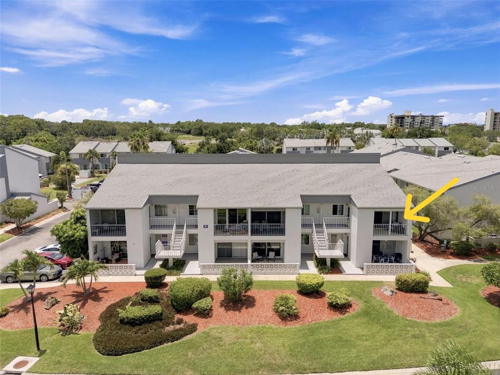 An exterior view of a two-story apartment building with a yellow arrow pointing to a balcony — 14800 WALSINGHAM ROAD UNIT 614, LARGO, FL