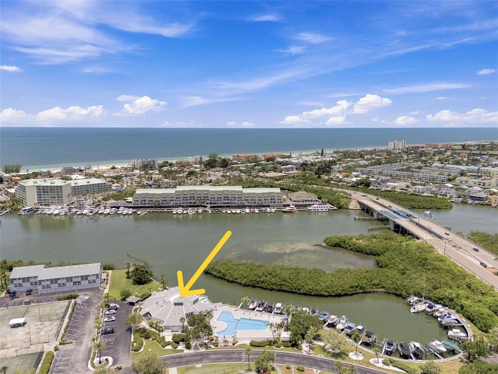 An aerial view shows a waterfront clubhouse with a pool and boat slips — 14800 WALSINGHAM ROAD UNIT 614, LARGO, FL