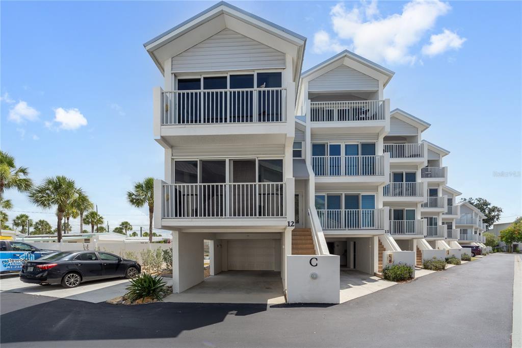 A row of multi-story townhouses with elevated garages and balconies under a blue sky — 2255 N BEACH ROAD UNIT 12, ENGLEWOOD, FL