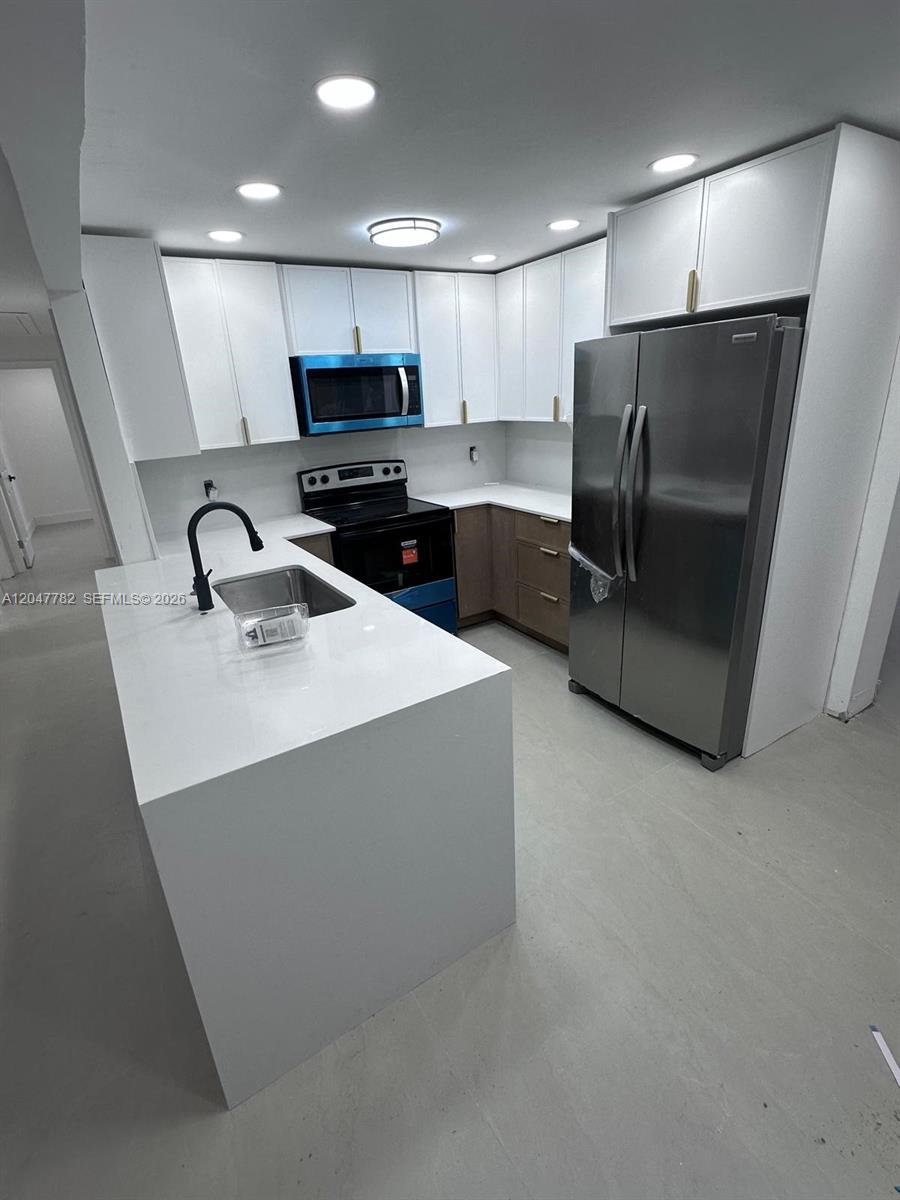 A modern kitchen features white cabinets, stainless steel appliances, and a white quartz island — 4380 SW 49th Ct # 0, Dania Beach FL 33314, DANIA BEACH, FL