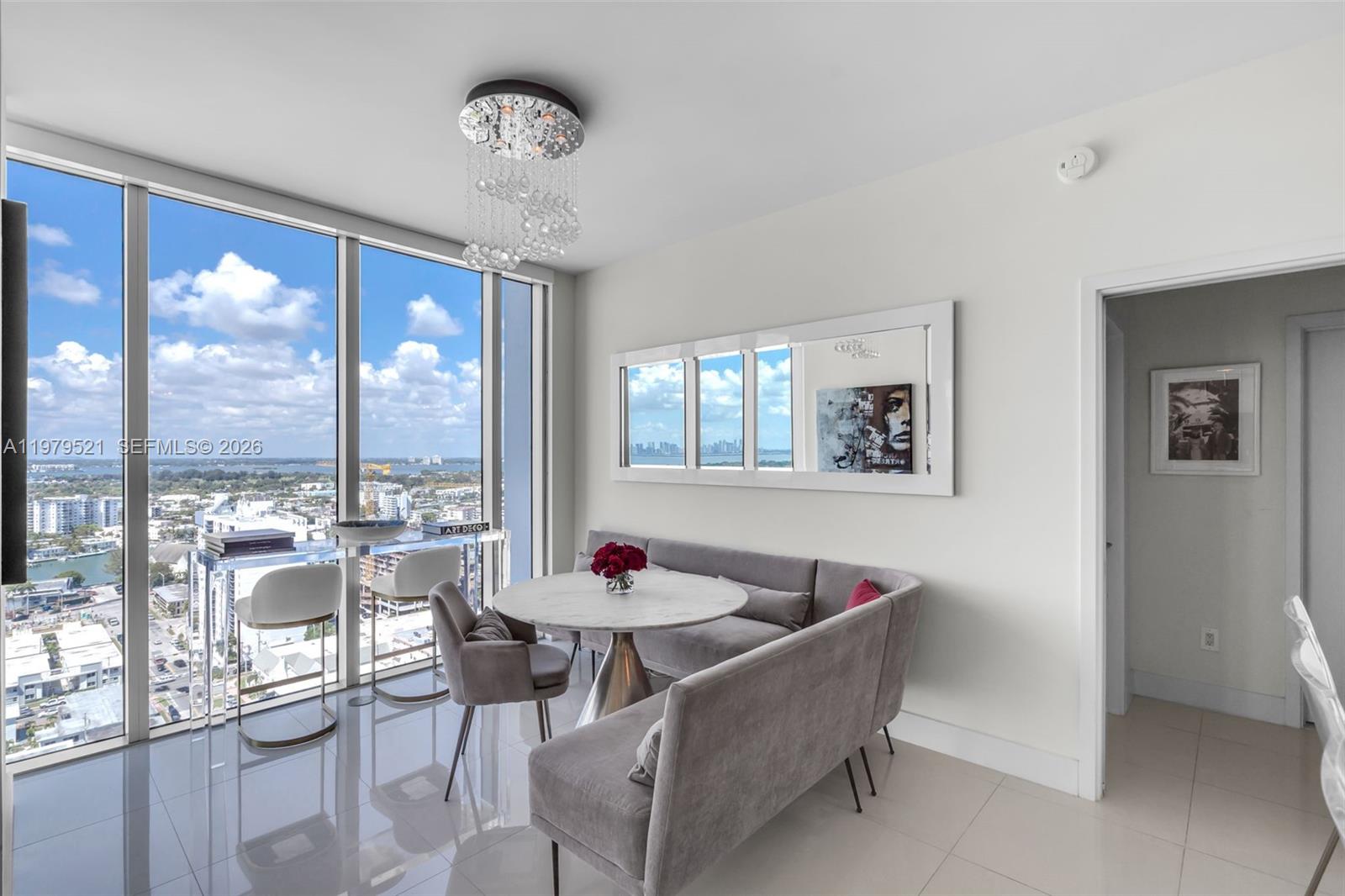 A dining area features a marble table, grey banquette seating, and floor-to-ceiling windows with city views — 6899 Collins Ave # 2403, Miami Beach FL 33141, MIAMI BEACH, FL