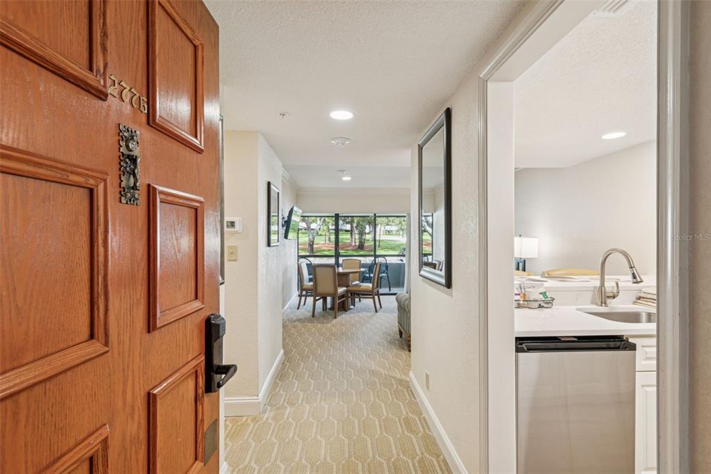 An entryway leads into a dining area with a view of trees through large windows — 36750 US HIGHWAY 19 N UNIT 13207, PALM HARBOR, FL