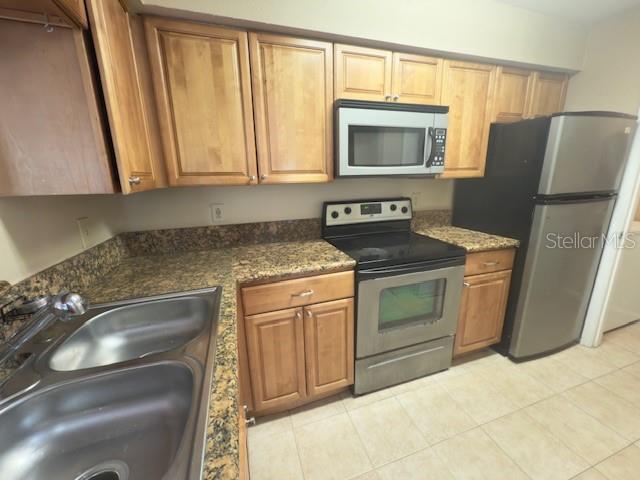 A kitchen features wood cabinets, granite countertops, stainless steel appliances, and a double sink — 208 AFTON SQUARE UNIT 10-307, ALTAMONTE SPRINGS, FL