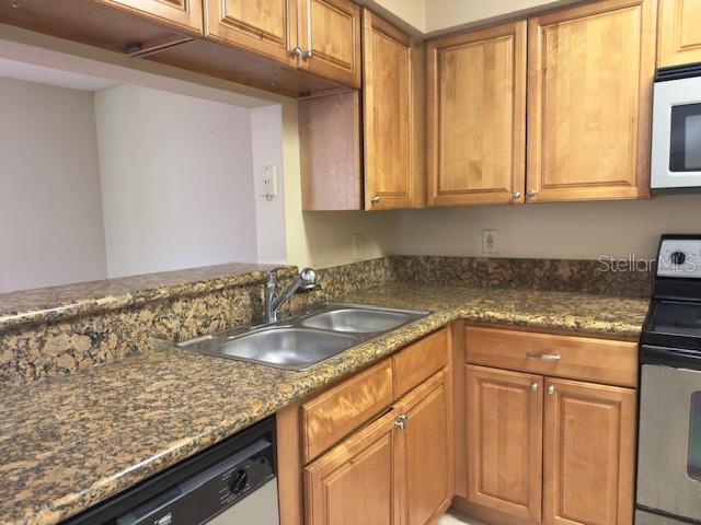 A kitchen features light wood cabinets, granite countertops, a double sink, and stainless steel appliances — 208 AFTON SQUARE UNIT 10-307, ALTAMONTE SPRINGS, FL